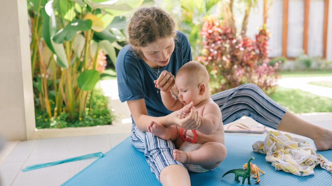 Maman qui joue avec son bébé sur la terrasse sous la pergola